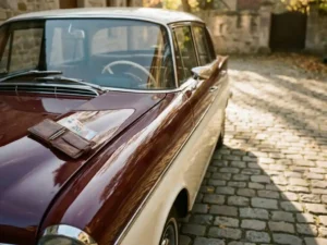 Vintage jaren '60 klassieke auto op kasseienoprit met leren portemonnee en eurobiljetten op de gepolijste motorkap.