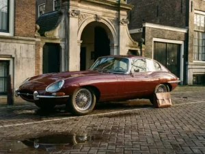 Vintage jaren '60 Mercedes op kasseiweg voor Amsterdams grachtenpand, bordeauxrode lak en chromen details in gouden middagzon.